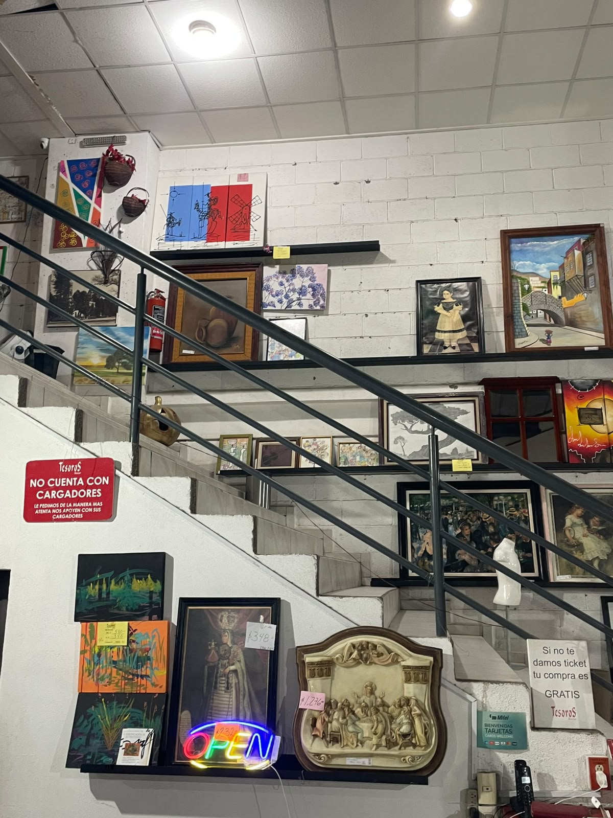 Pared de arte y antigüedades en la escalera de Tesoros Bazar